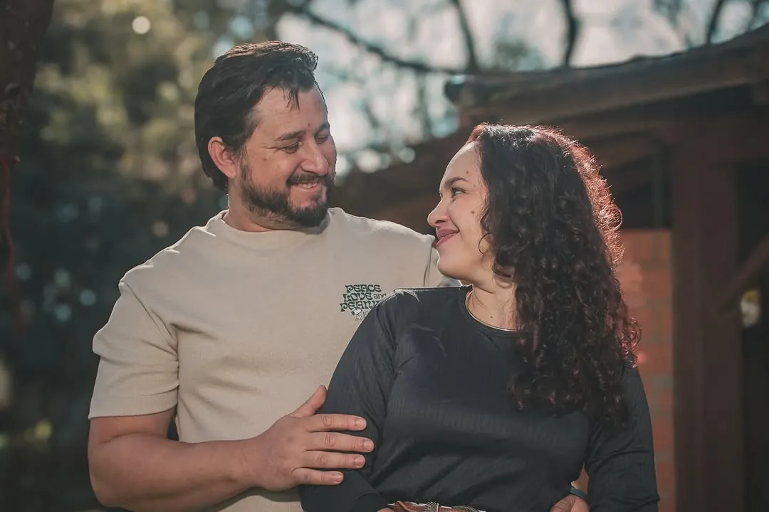 Casal se olhando e sorrindo ao ar livre
