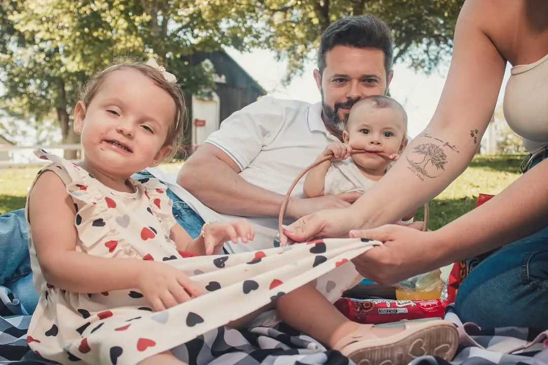 Família em piquenique no parque, criança sorrindo em primeiro plano