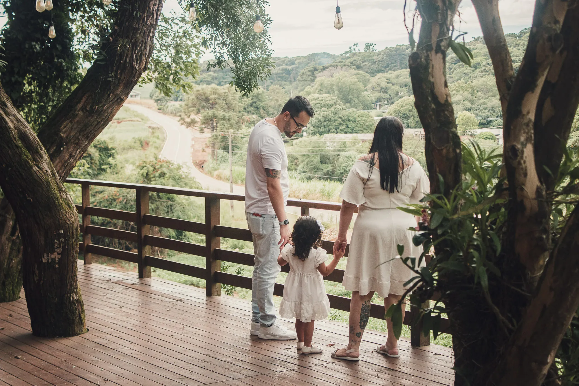 Família de costas numa varanda de madeira, olhando o vale