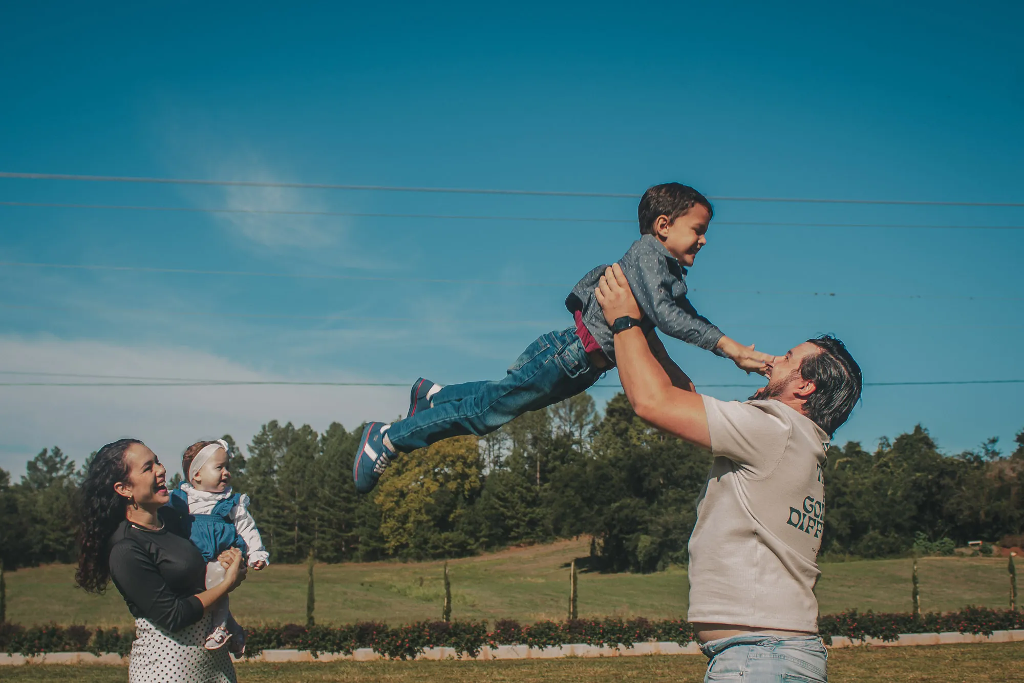 Pai joga o filho para o alto num campo