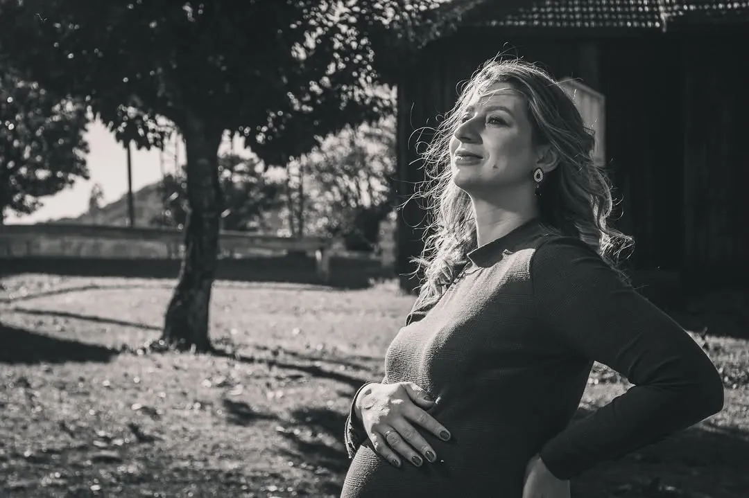Gestante em preto e branco, de perfil, sob a luz do sol
