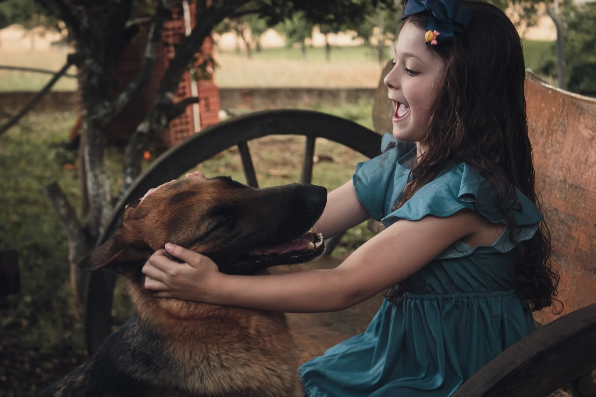 Menina de vestido azul brincando com um cachorro