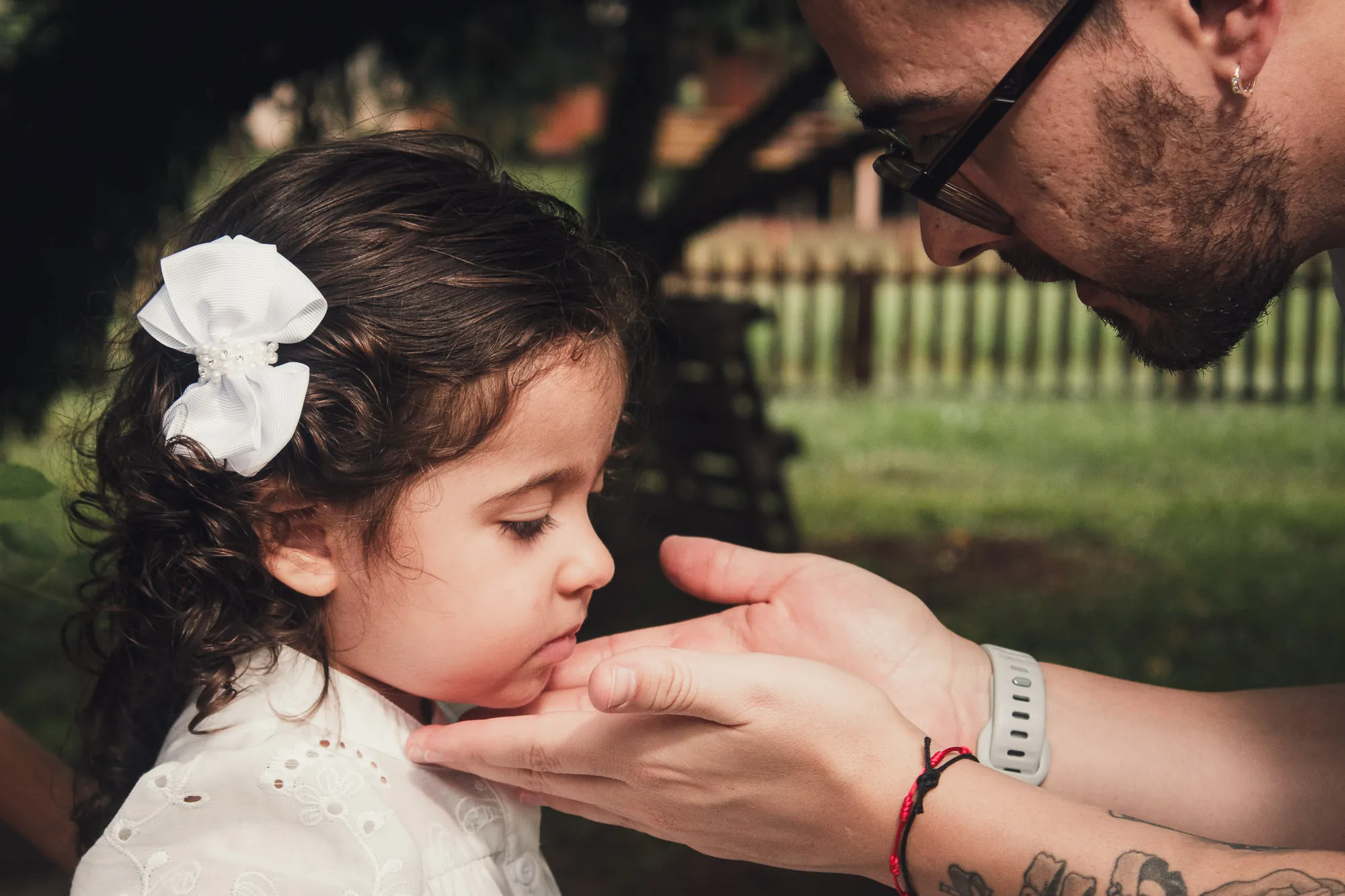 Pai segura o rosto da filha pequena com carinho