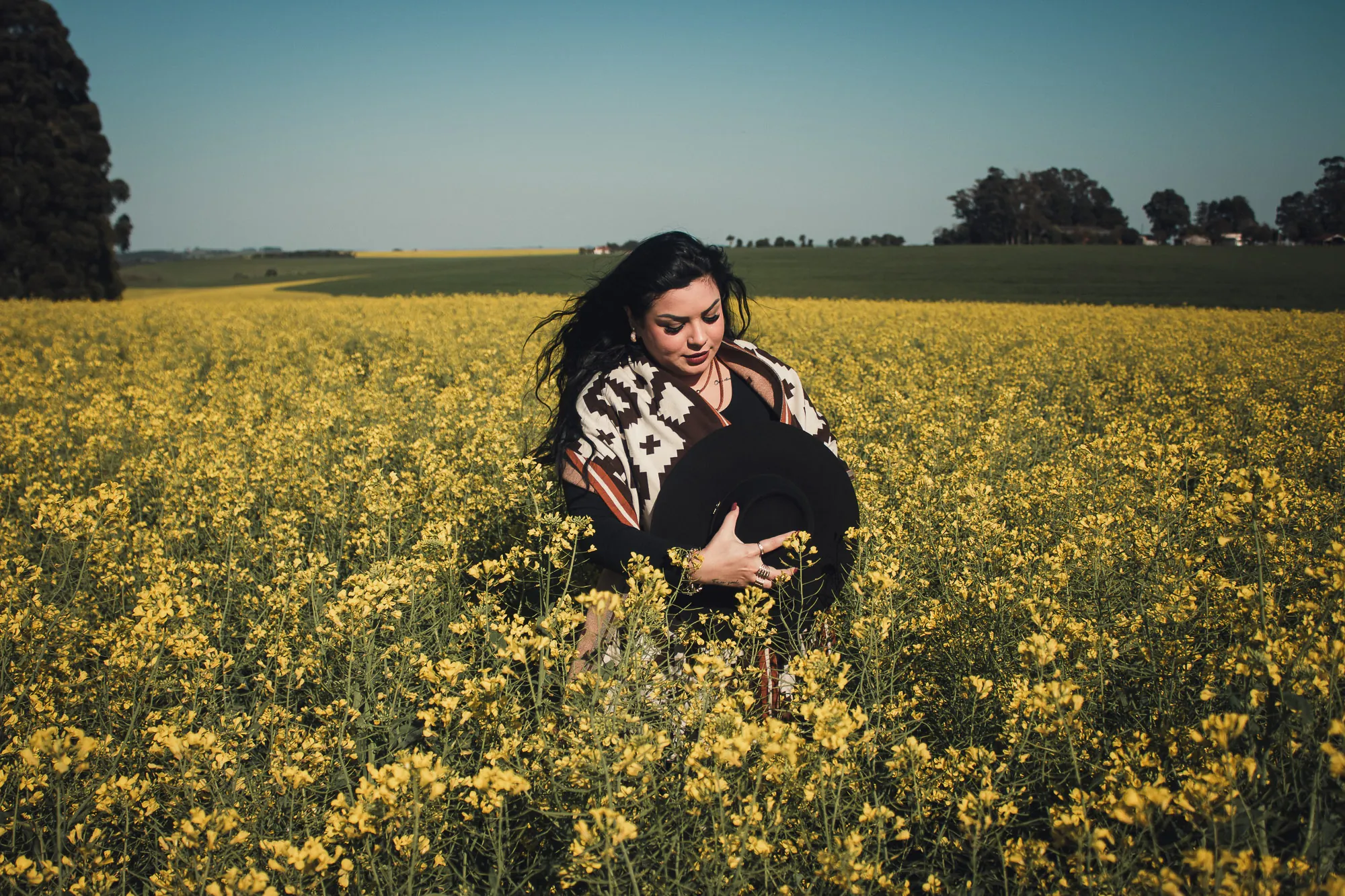 Mulher de poncho em campo de flores amarelas