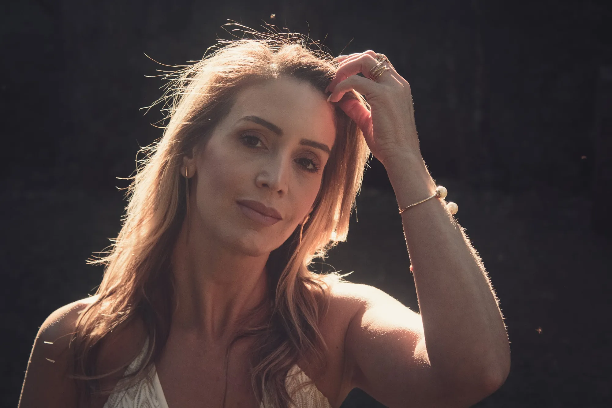 Mulher loira em contraluz, mão no cabelo