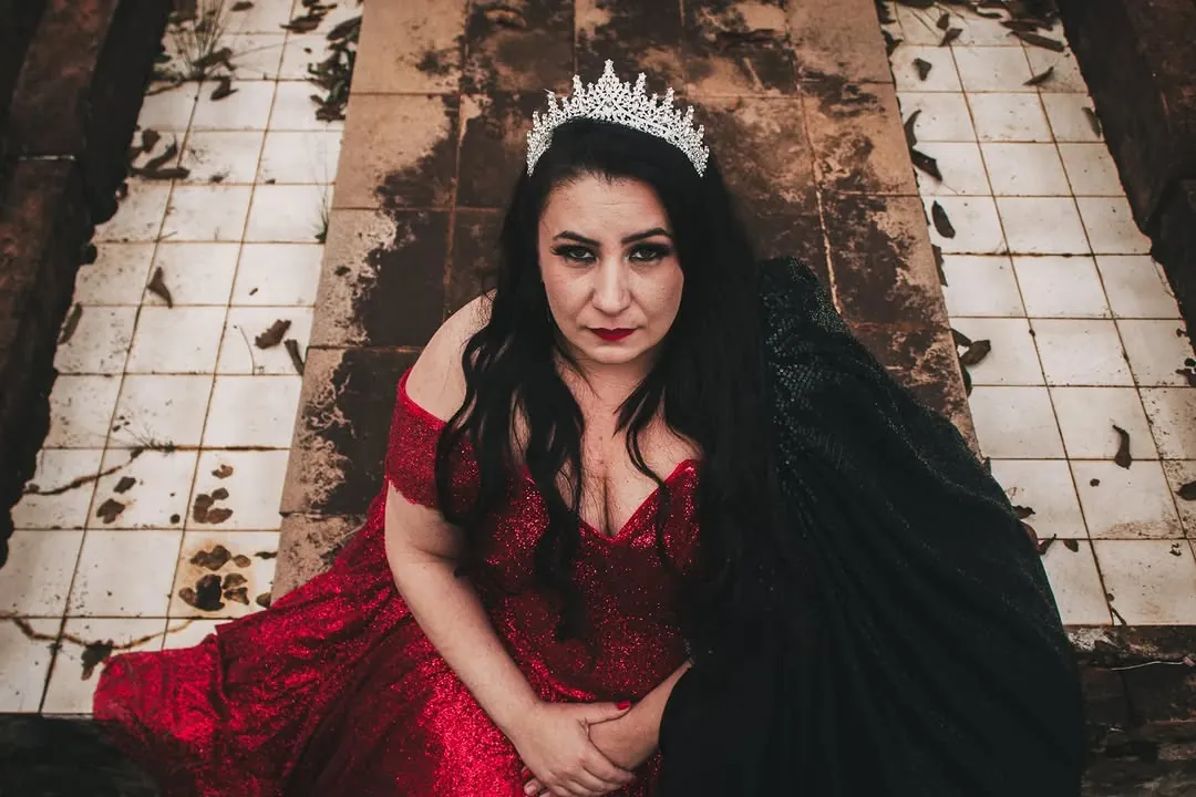 Mulher de vestido vermelho e coroa olhando para a câmera